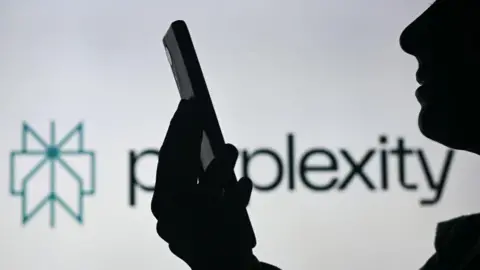 BBC threatens AI firm with legal action over unauthorised content use - BBC threatens AI firm with legal action over unauthorised content.webp Getty Images A silhoutted figure is shown holding their smartphone and looking at it in front of a white background displaying the Perplexity logo.