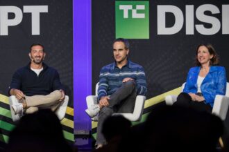 Three speakers talk on a stage with a black backdrop.